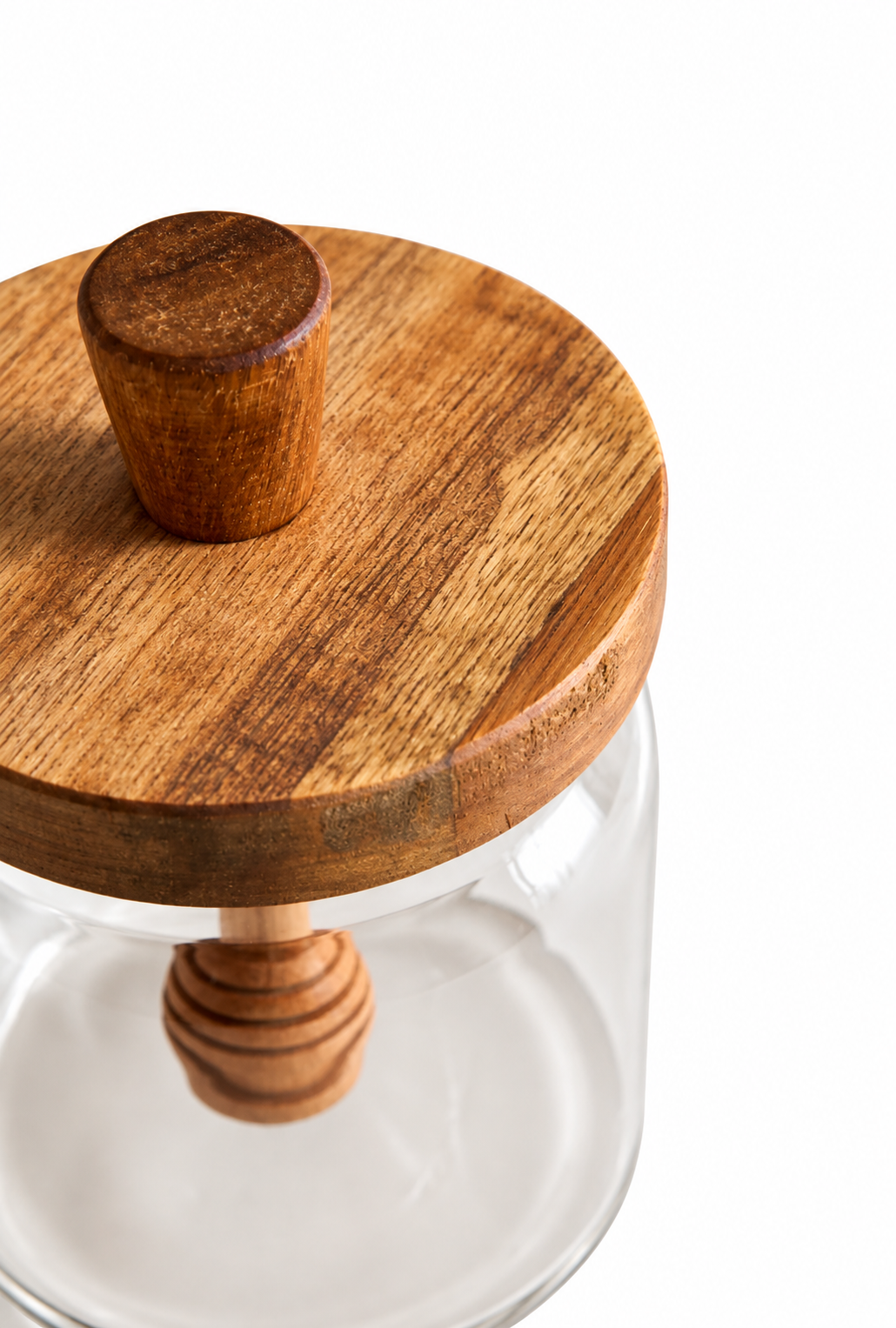 A close-up of a clear glass jar with a round wooden lid and a small wooden knob, shown on a white background.